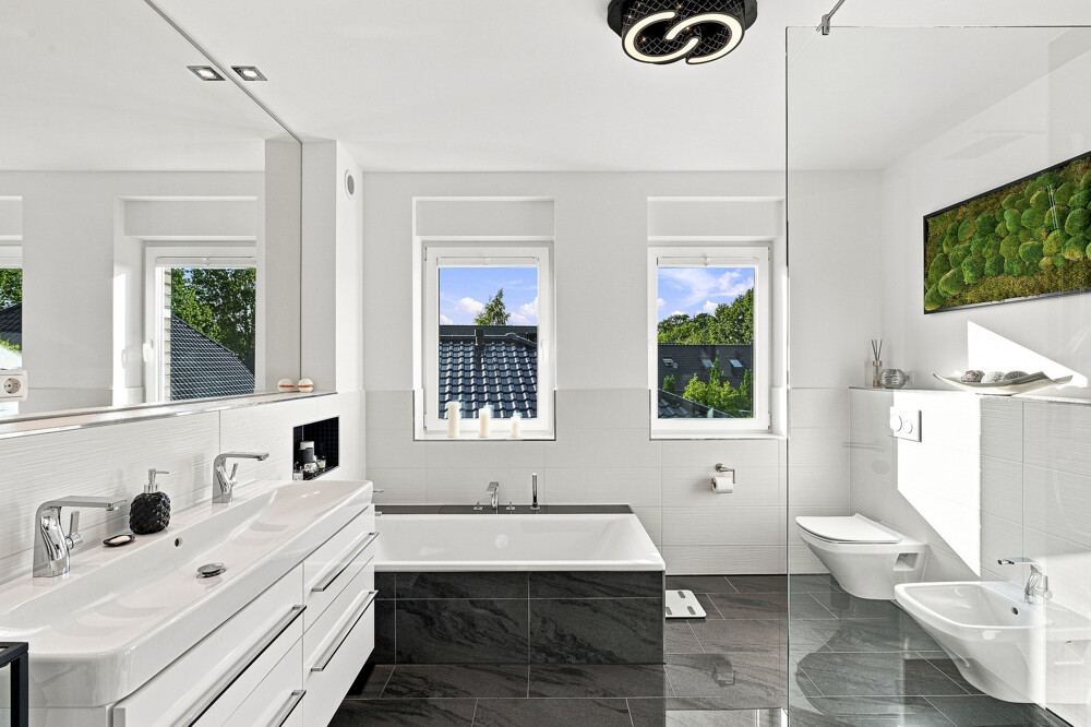 Badezimmer des Stadthauses in Bad Bramstedt mit Badewanne und Doppelwaschtisch.