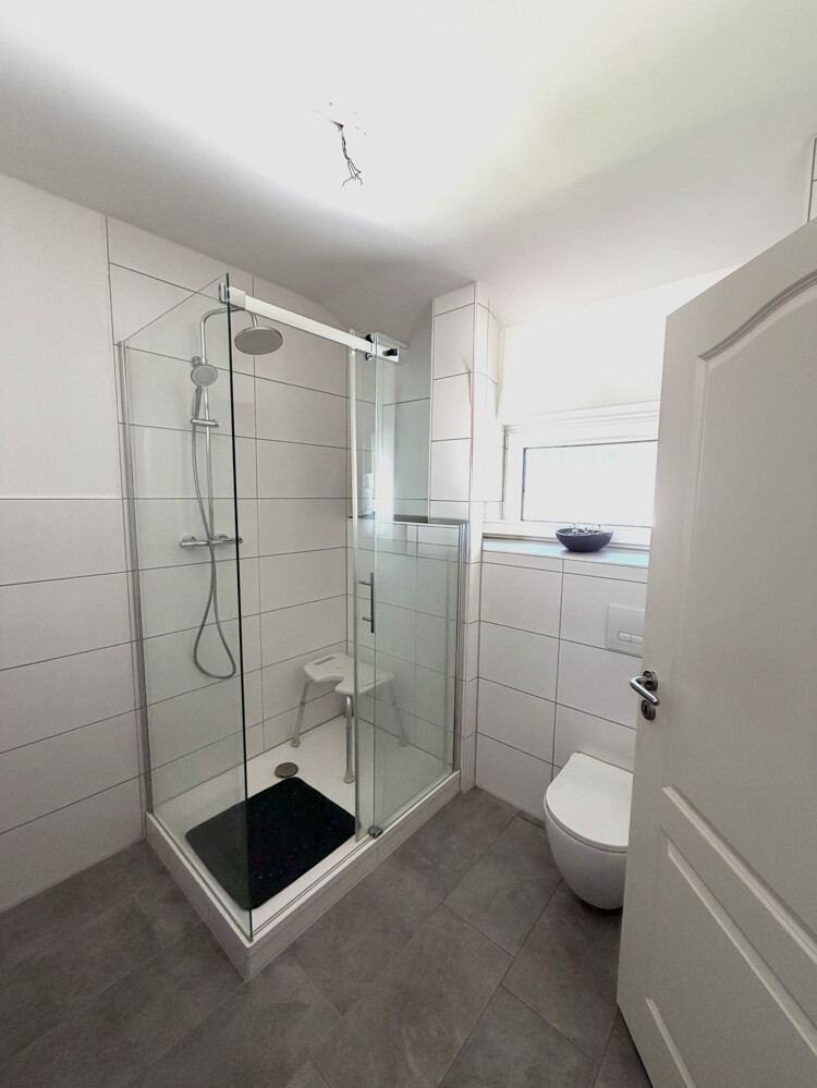 Badezimmer der Wohnung in Hemdingen mit Dusche und Fenster.