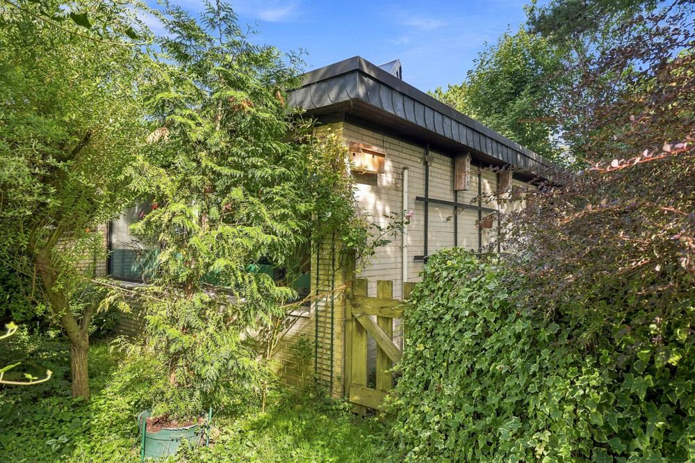 Seitliche Ansicht des Bungalows in Henstedt-Ulzburg mit hellem Klinker und Flachdach.
