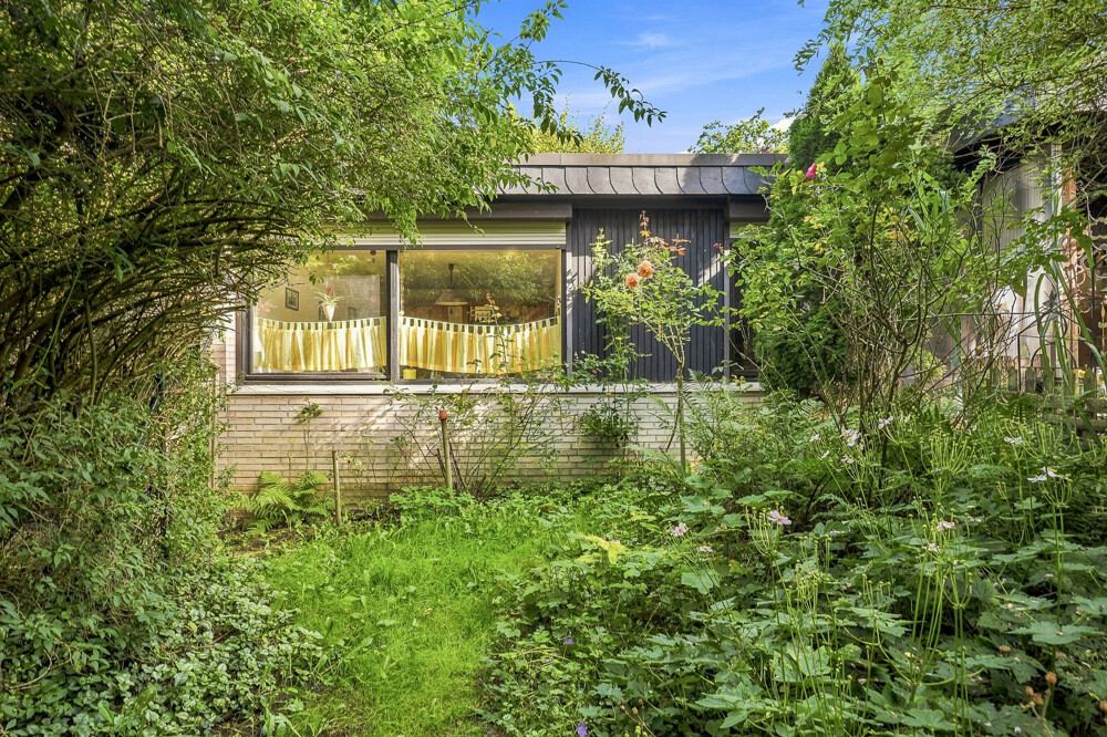 Gartenseite des Bungalows in Henstedt-Ulzburg mit breitem Fenster zum Wohnbereich.