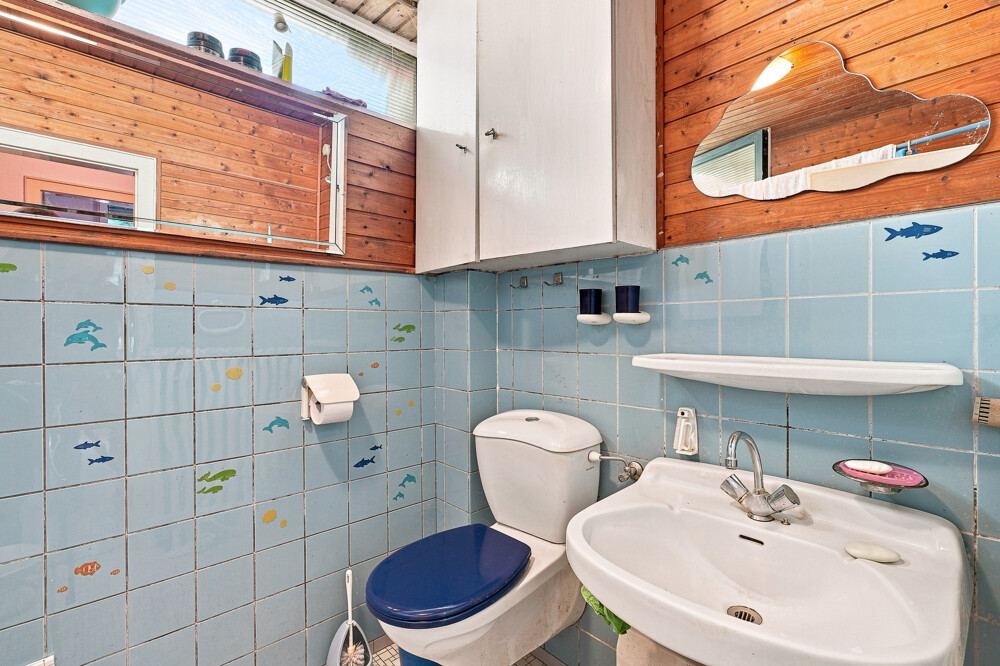Badezimmer des Bungalows in Henstedt-Ulzburg mit Waschbecken, WC und Fenster.