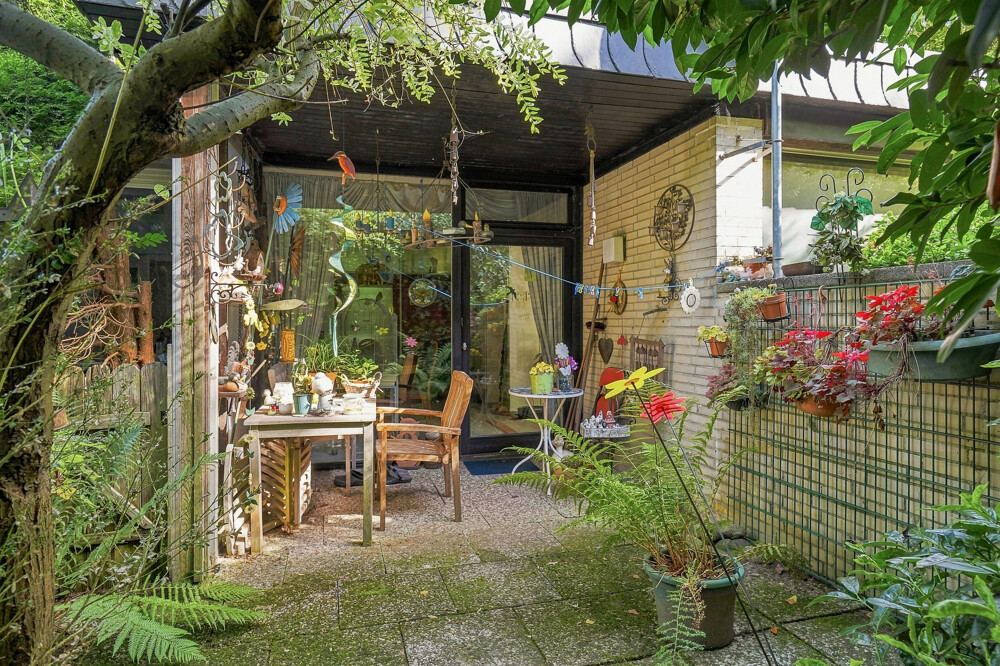 Überdachte Terrasse des Bungalows in Henstedt-Ulzburg mit Sitzplatz und Bepflanzung.